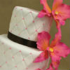 White cake with black ribbons and pink flowers