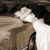 Couple poses a top of vintage Lincoln