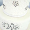 Elegant white three tier cake with metallic buttercream design & fresh floral topper
