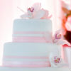 Five tier white fondant cake with pink fondant ribbon trim & orchid topper