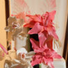 White four tier square cake with black and green ribbon fondant, piped pearl beading and white and coral floral accents