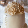 Traditional four tier cream cake with embellished bow, pearl bead trim and peach roses