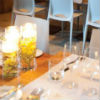 Floating tea light centerpieces, yellow floral accents, wood tables