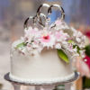 White four tier cake with piped accents and pink and white floral accents
