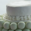 Four tier white cake with green and pink pastel accents