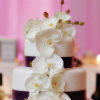 Modern four tier cake with cascading orchids and purple ribbon trim