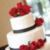 Modern elegant white cake with black ribbon trim and red fondant roses