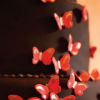 Romantic three tier dark brown fondant cake with petite red and gold fondant butterflies
