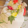 Two tier white cake with pearl bead trim, vine accent and kissing couple topper