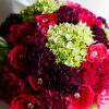Bright coloured bouquet with pink and mauve carnations, fuchsia roses, green flowers and jeweled accents.
