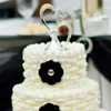 Three tier white cake with woven icing, clear bead trim, black floral accents and metal heart topper
