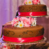 Five single tier chocolate brown cakes on pedestals of varying height with pink trim and white and pink floral accents 