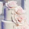 Simple three tier white cake with cascading pink roses and metallic stencil design